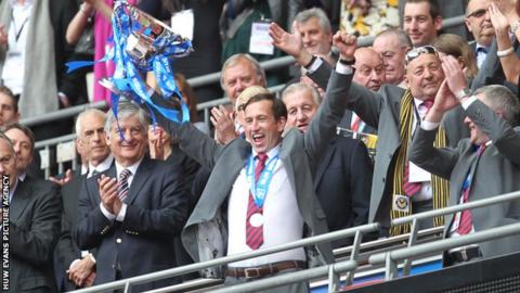 Justin Edinburgh lifts the Conference play-off trophy in the air