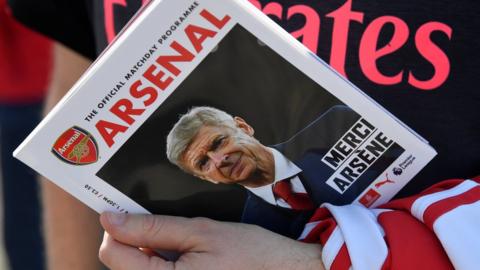 Arsenal fan holding the match day programme