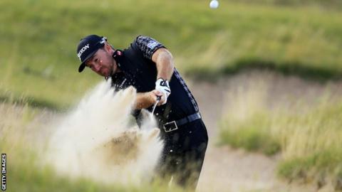 Graeme McDowell plays out of a bunker at the 16th in the first round