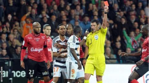 Majeed Waris (centre) is shown the red card by the referee