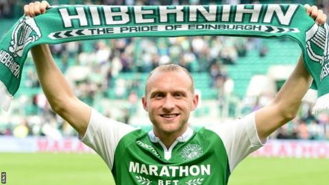 Dylan McGeouch holds a Hibernian scarf aloft