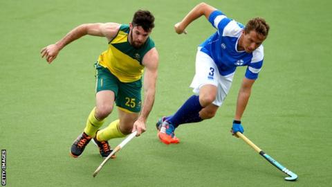 Trent Mitton of Australia is challenged by Scotland's David Forsyth during the Glasgow 2014 men's preliminaries pool match between Australia and Scotland at the Glasgow National Hockey Centre