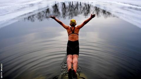 Woman diving into a pool cut into a frozen lake