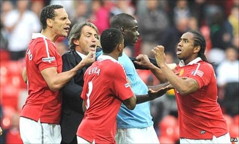 Mario Balotelli (centre) is confronted by United players Anderson (right) and Rio Ferdinand (left) and Patrice Evra (foreground), while City manager Roberto Mancini (second left) attempts to intervene