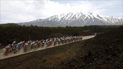 Cyclists pedal as the Etna volcano is seen in background
