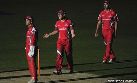 Glamorgan players wait in the dark for play to restart