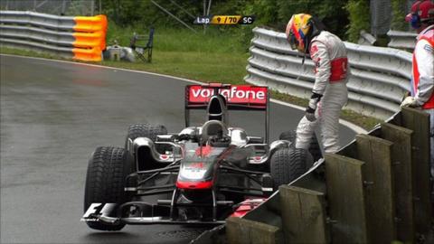 Lewis Hamilton looks at his McLaren after colliding with Jenson Button