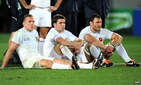 France players Imanol Harinordoquy, Dimitri Yachvili and Lionel Nallet sit dejectedly on the ground after their defeat