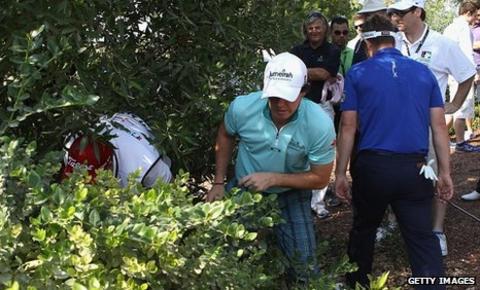 Luke Donald (right) helps Rory McIlroy search for his ball on the second hole