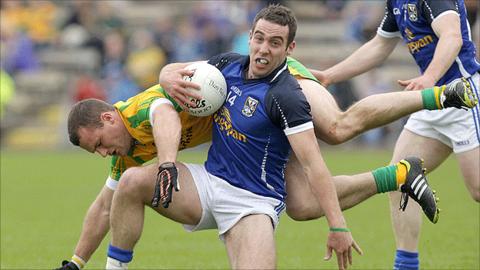 Cavan's Eugene Keating holds on to the ball as Neil McGee of Donegal hits the deck