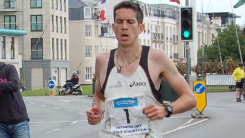 Lee Merrien crosses the line at the Guernsey half marathon