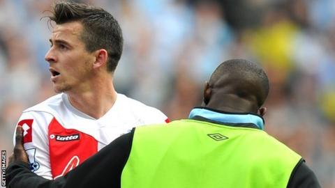 Joey Barton is restrained by a Manchester City substitute
