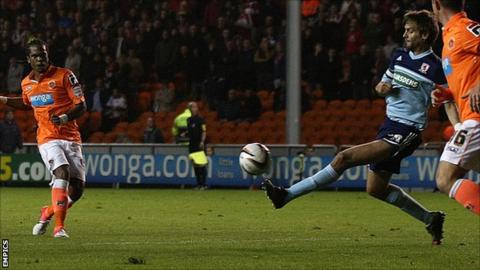 Nathan Delfouneso scores for Blackpool despite Jonathan Woodgate's attempt to block the shot