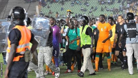 Police escort Ivory Coast players off the pitch in Dakar