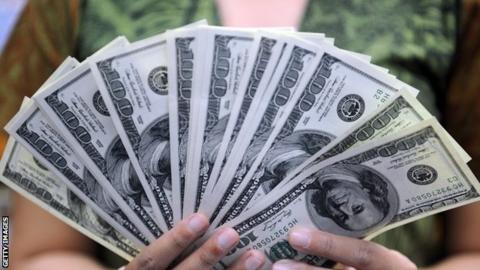 A cashier holds 100 USD notes