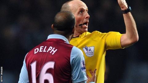 Fabian Delph is booked for deliberate handball by referee Mike Dean