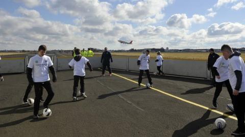 Pupils play football on the runway