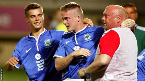 David Jeffrey embraces Linfield goalscorer Aaron Burns with Matthew Clarke also in the picture
