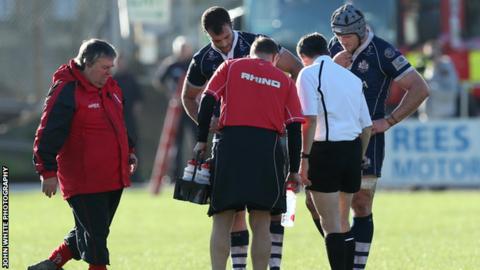 Players and officials look at the hole in the pitch during Aberavon v Bristol