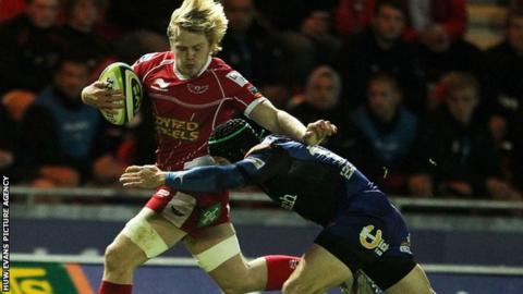 Scarlets' Daniel Thomas is tackled by Dragons fly-half Kris Burton
