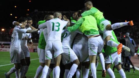 Algerian players celebrate winning their World Cup play-off against Burkina Faso