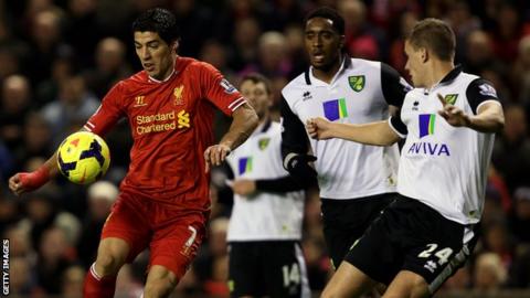 Luis Suarez of Liverpool eludes a host of Norwich City players