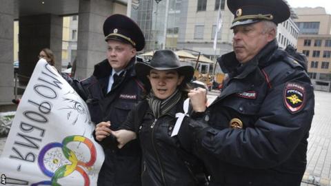 A protester is led away by Russian police officers