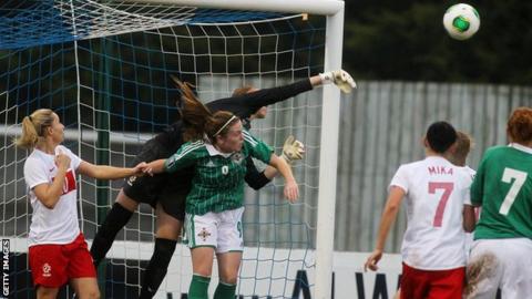 Poland goalkeeper Katarzyna Kiedrzynek clears a cross while under pressure from Northern Ireland's Simone Magill