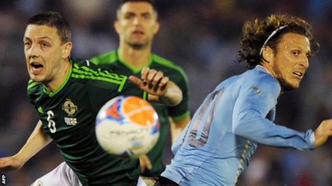 Northern Ireland's Chris Baird competes against Diego Forlan of Uruguay