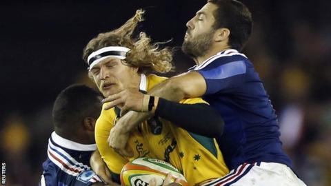 Australia's Nick Cummins is tackled by two French defenders