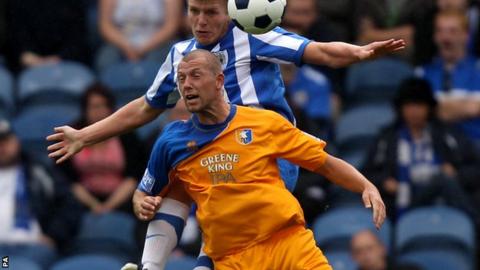 Stockport County's Carl Piergianni and Mansfield Town's Ross Dyer battle for possession of the ball in the air