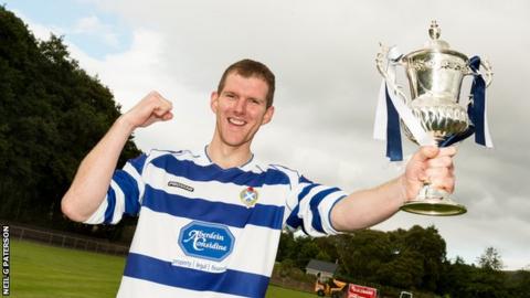 Fraser MacKintosh celebrates with the trophy after scoring Newtonmore's winner in the Artemis MacAulay Cup final against Kyles Athletic