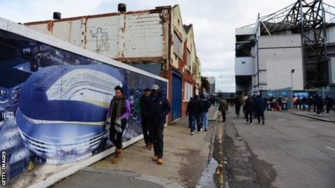 Fans walk past a mural depicting design for a new Tottenham Hotspur stadium