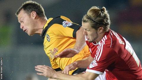 Michael Flynn of Newport County and Jake Reeves of Swindon compete