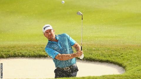 Graeme McDowell plays out of a bunker during the third round in Kuala Lumpur