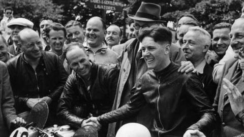 Well-wishers congratulating motorcyclist Geoffrey Duke on his victory in the Isle of Man Tourist Trophy Race (1950)