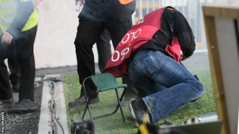 Photographer Daren Kidd falls after being struck during the match at Windsor Park