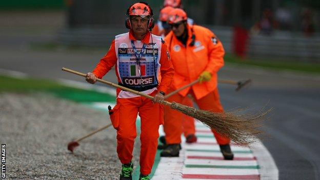 Marshals sweep off gravel from the track during the first practice day at Monza
