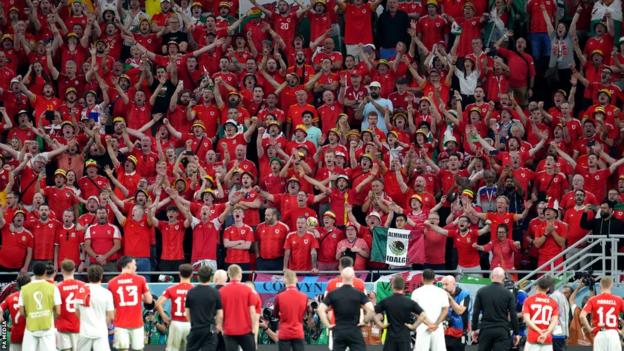 Wales players and staff salute the Red Wall of their fans after their World Cup exit