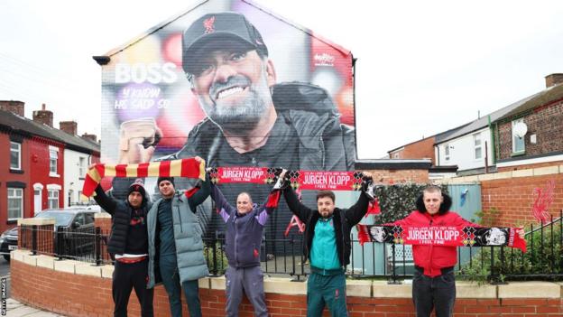 Liverpool fans pose in front of the Jurgen Klopp mural before the Reds' FA Cup tie at home to Norwich