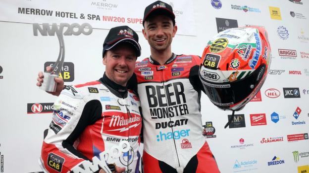 Alastair Seeley and Glenn Irwin shake hands and walk together after exchanging words after the final Superbike race