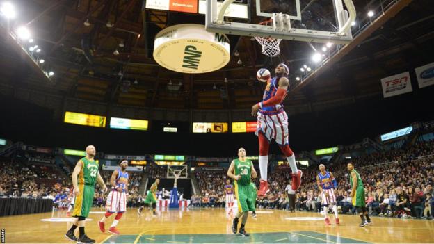 A clutch of Washington Generals players watch on as a Harlem Globetrotter dunks against them
