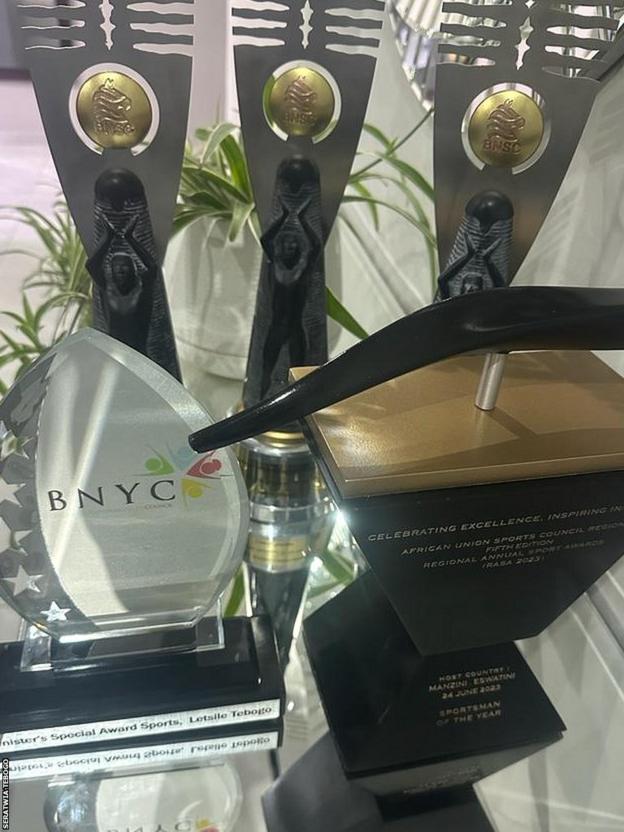 A collection of trophies sit on a glass table