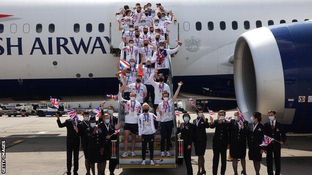 Team GB athletes pose with medals getting off a plane