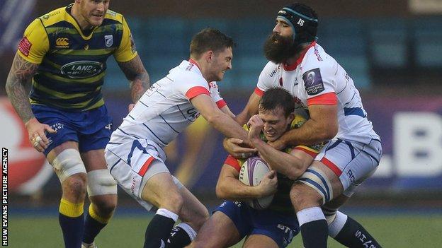 Garyn Smith of Cardiff Blues is held by Josh Strauss of Sale Sharks and Will Cliff of Sale Sharks