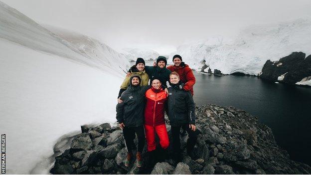 Anders Hofman und sein Support-Team posieren nach Abschluss des Ironman-Triathlons in der Antarktis für ein Foto