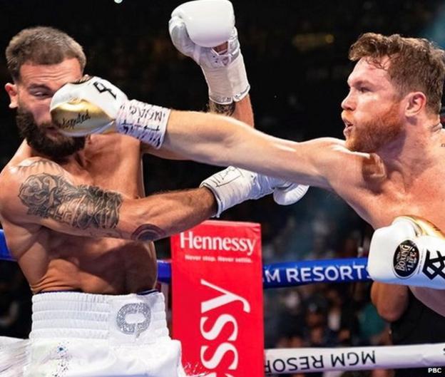 Saul 'Canelo' Alvarez punches Caleb Plant with the word 'undisputed' written on his gloves