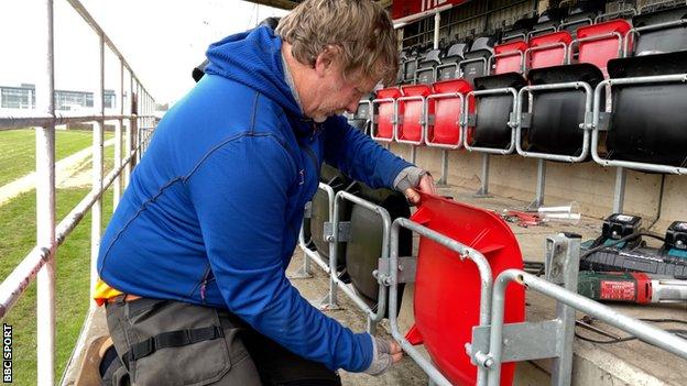 Seorang pria memasang kursi di stadion Bridgwater