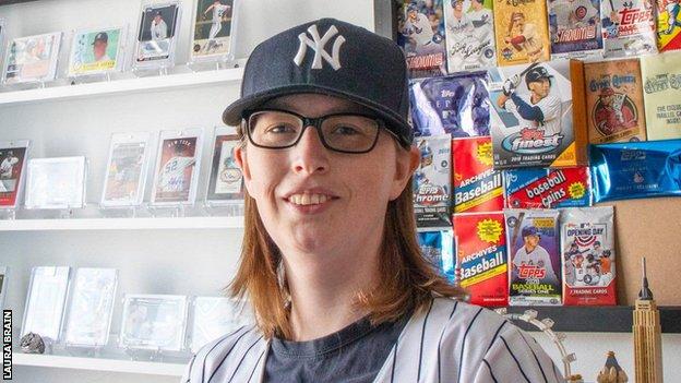 Laura Brain in front of her sports cards and memorabilia collection