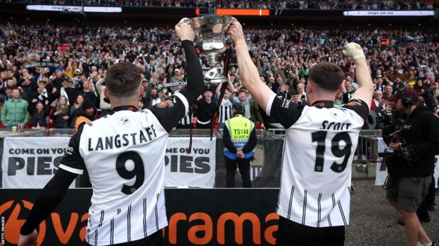 Macaulay Langstaff and Cedwyn Scott of Notts County celebrate with National League play-off final trophy in front of their fans at Wembley